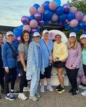 Image of a group of people standing in front of a balloon arch
