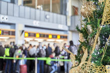 Flying in Christmas concept. Detail of big Christmas tree with golden ornaments with line of people in background