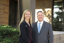 Photo of woman with blonde hair standing next to man with gray hair outside a building