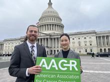 Two people stand in front of the U.S. Capitol building holding an AACR sign, with Subin Kim on the right.