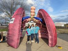 Three people standing in front of an inflatable lung. 