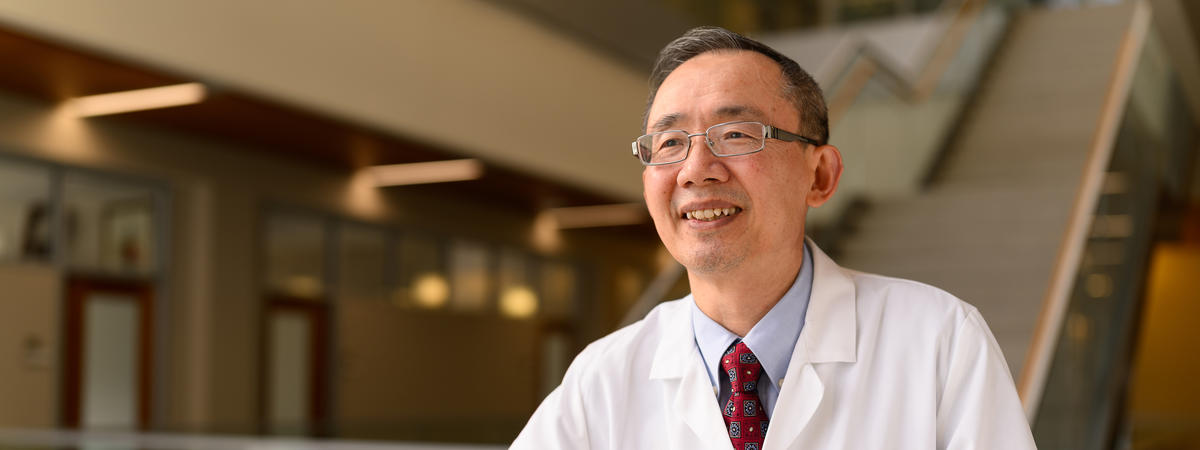 Male physician in white coat smiling at camera in medical office setting