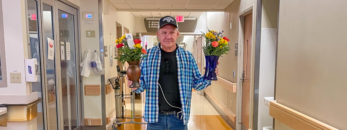 Image of Bobby Patton holding bouquets of flowers in a hospital corridor. 