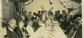 A large group of people gathered around a long, decorated table at a celebratory event.