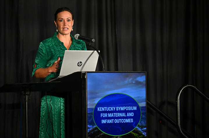 a woman in a green dress stands behind a podium while giving a speech