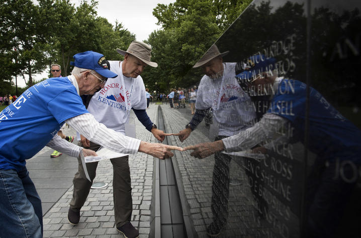 Photo of A UK Honor Flight veteran and guardian searching for names on the Vietnam Veterans Memorial. 