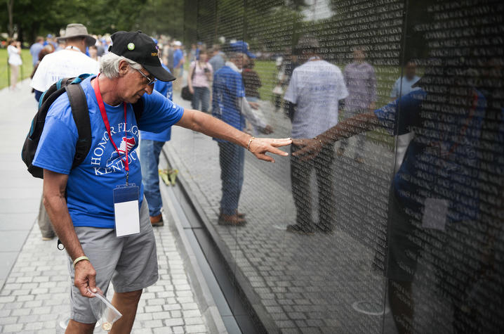 Photo of A UK Honor Flight veteran and guardian searching for names on the Vietnam Veterans Memorial. 