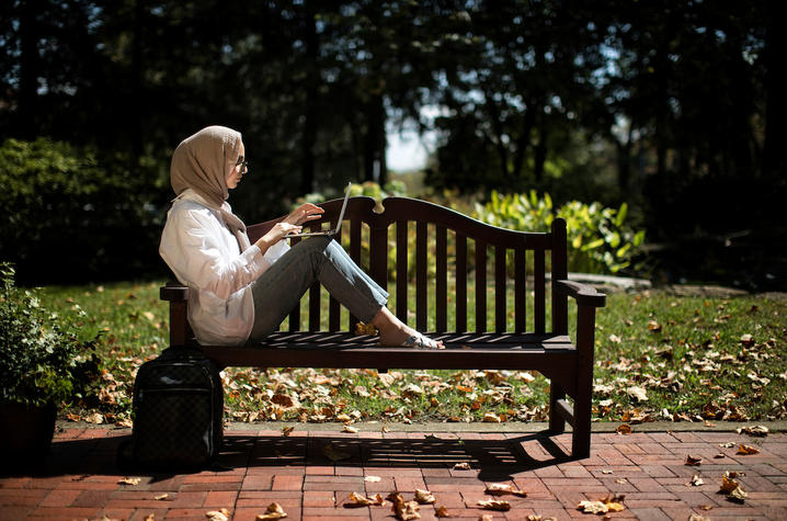 Student sits on bench on campus