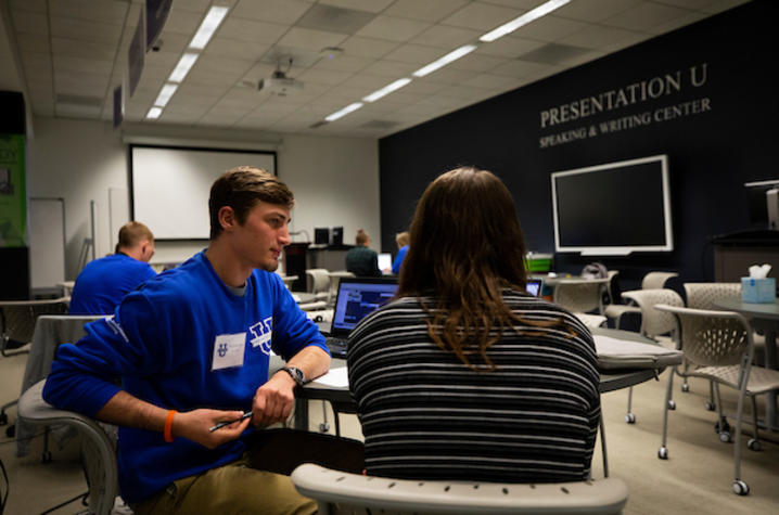 photo of student employee at PresentationU working with another student