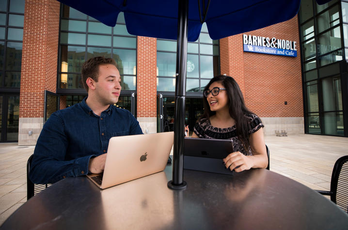 Two students using an iPad and laptop. 