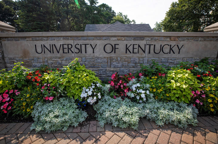 photo of stone wall at campus entrance that says "University of Kentucky" and has blooming flowers in front of it