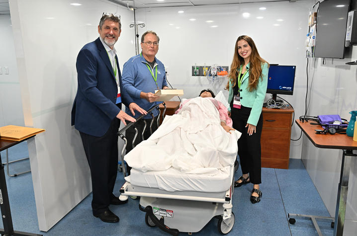 Three people stand around an OB simulation in a mobile clinic