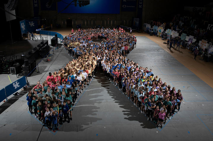 DanceBlue marathon dancers in the formation of the DanceBlue gold ribbon logo.