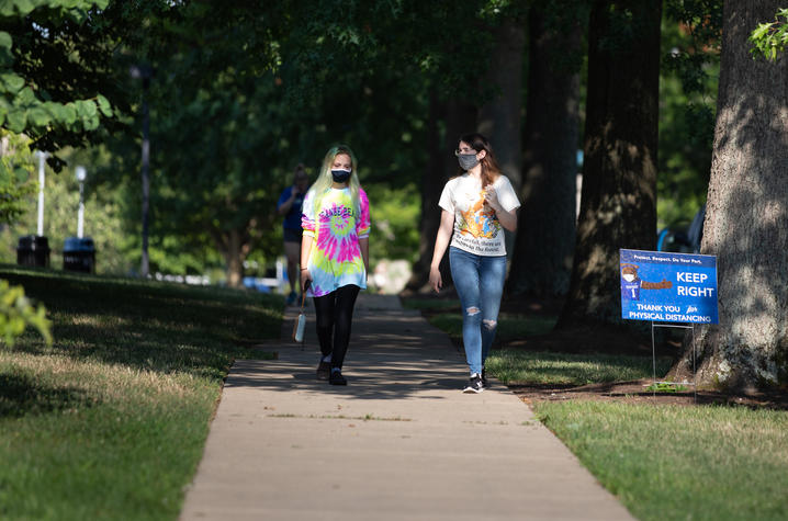 Image of two students walking on campus wearing face masks