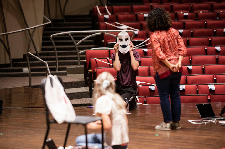 photo of student holding up their Greek mask to their face for Nancy Jones to examine in TA 120