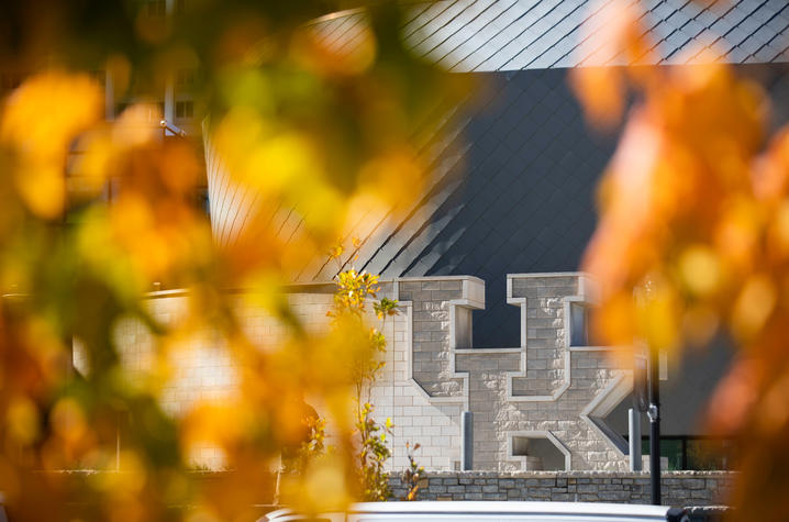 The large "UK" in front of the Gatton Student Center framed by fall foliage