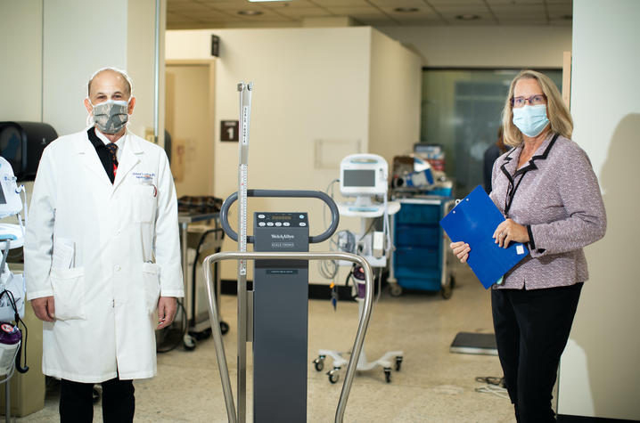 Principal Investigator Dr. Richard Greenberg and CCTS Clinical Operations Director Linda Rice, BSN, RN, CCRC. They are standing in a clinic several feet apart and are wearing face coverings. 