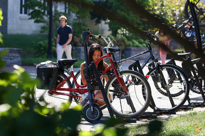 a student is securing her bike to the bike rack using a lock. 