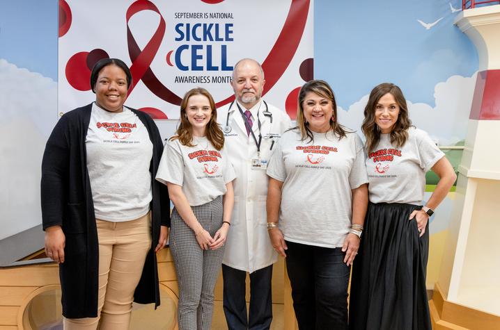 Image of Sickle Cell clinic team in front a banner for Sickle Cell Awareness Month