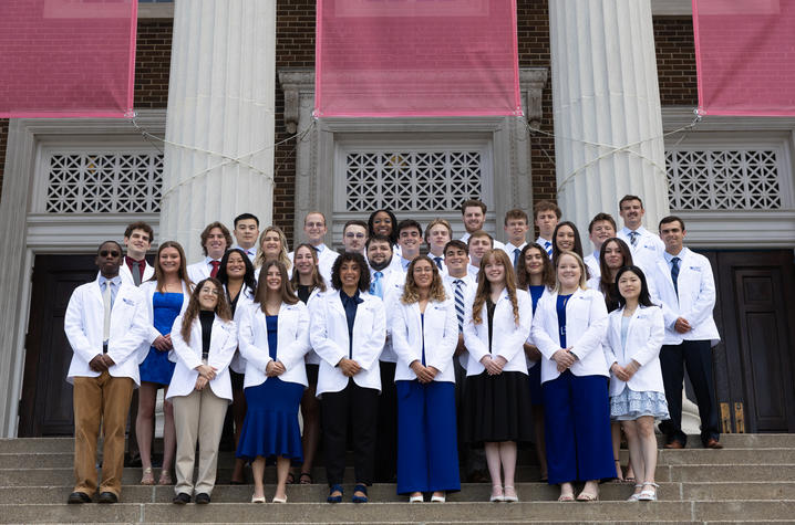 The image shows a large group portrait taken outdoors on the steps of a substantial stone building.