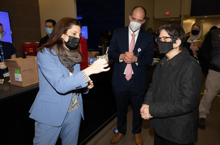 Woman showing COVID-19 vaccine to another woman with man in the background