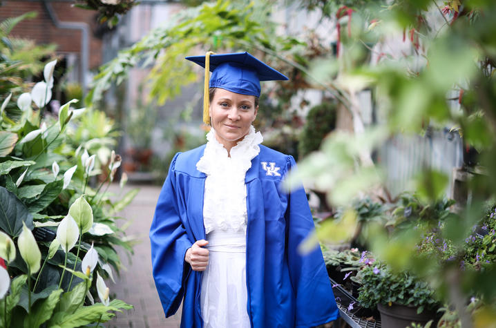 Angela Sanchez in UK cap and gown inside greenhouse