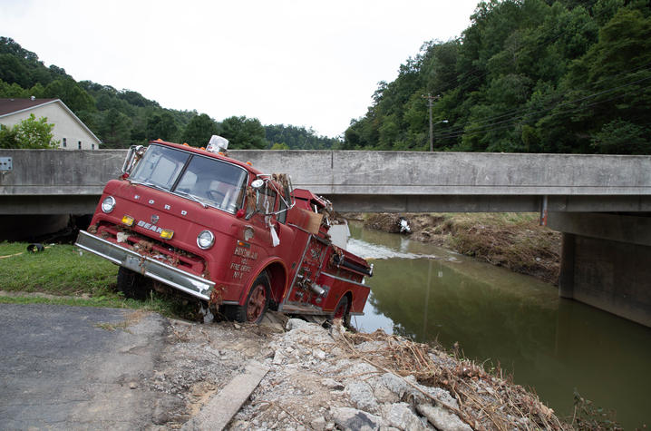 image of fire truck swept away by flood waters and stuck under a bridge