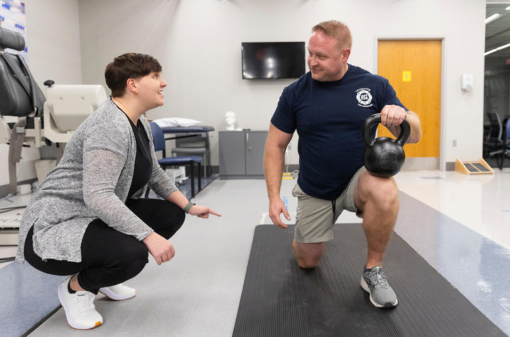 jen tinsley helping a firefighter with physical therapy using a kettlebell