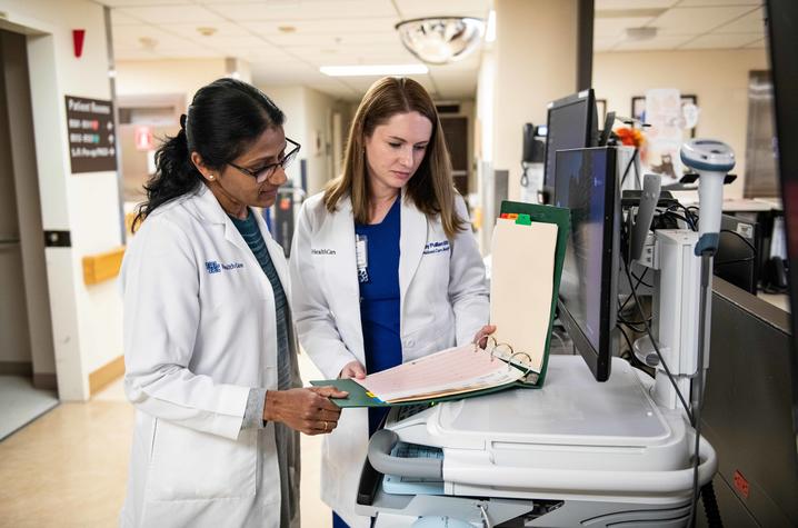 Dr. Padmaja Gaddam and Abby Pulliam look into a binder