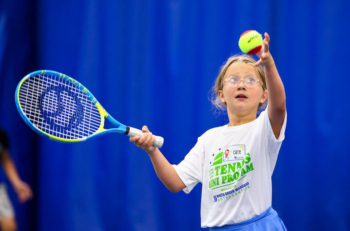 young child with tennis racket prepares to hit a tennis ball