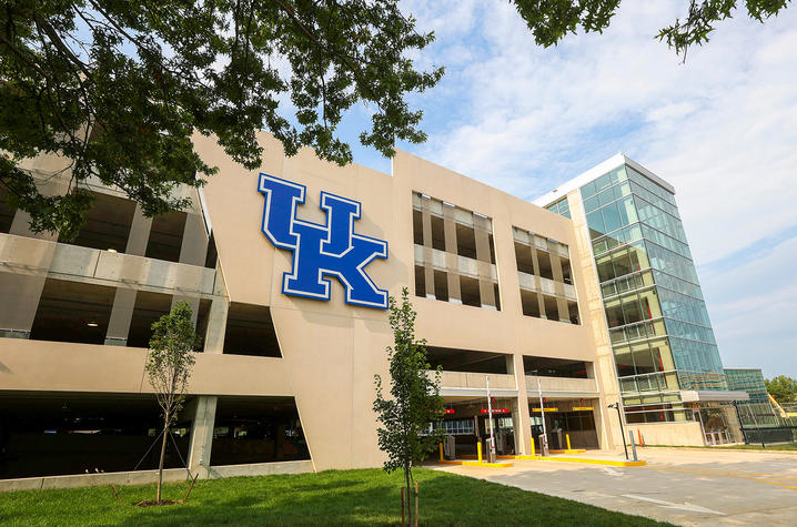 Exterior view of the University of Kentucky’s Sports Center Garage expansion, featuring a large blue UK logo on the parking structure beside a glass-enclosed stair tower.