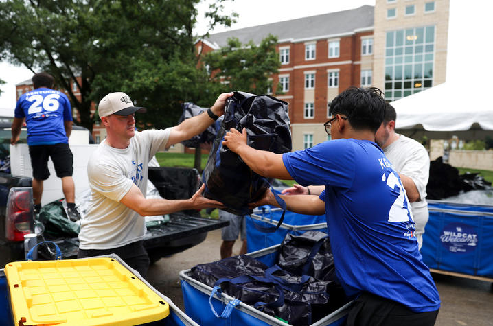 Volunteers transfer a large bag from a pickup truck into a blue cart during UK’s Big Blue Move-In.