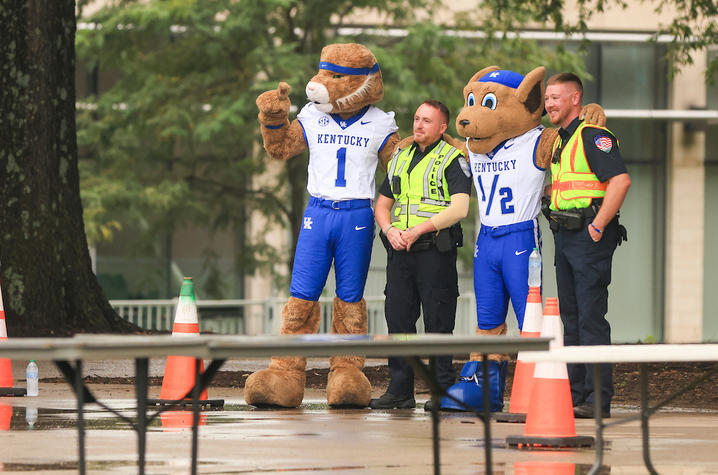 University of Kentucky mascots pose with two police officers along a rain-soaked move-in route.