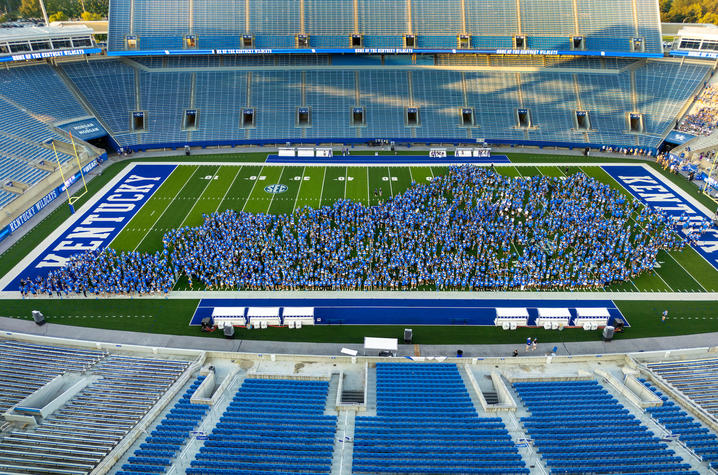 Hundreds of students gathered on Kentucky's football field pose to form a large “UK” logo inside a football stadium.