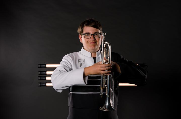 michael martorano standing and smiling for a marching band portrait with his trumpet