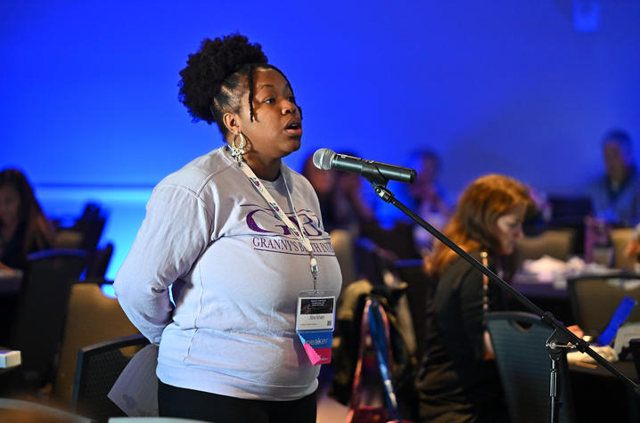Alexa Scisney steps up to a microphone to ask a question during the symposium