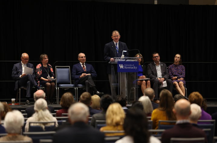 Man standing at podium with people sitting behind him on stage