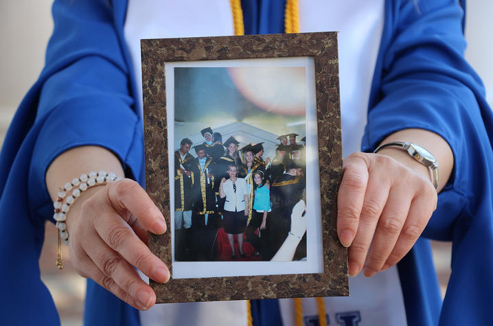 Photo of Madona Elias holding graduation photo from 2004.