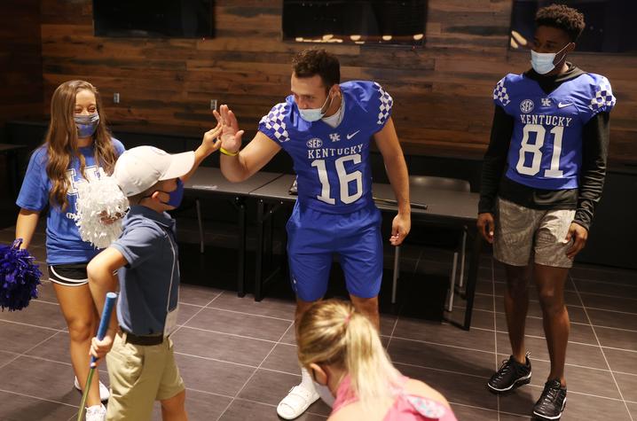 photo of football players high-fiving young golfers
