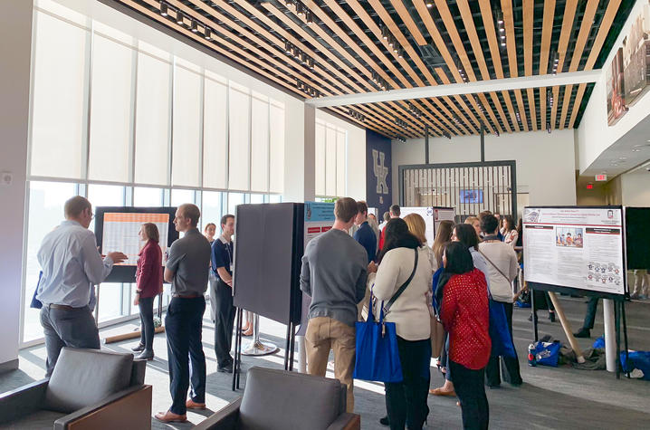 People standing and looking at research project boards. 