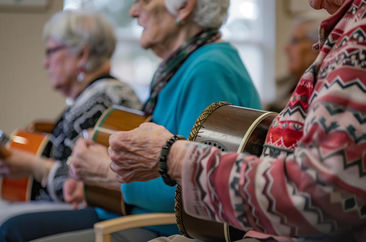 photo of group music therapy Three older adults sit side by side, playing hand drums, as part of a small group music session or recreational activity in a community or senior center.