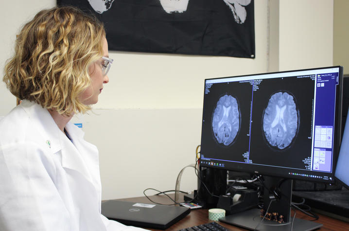 Alex Helman sits at her desk looking at images of brain scans on her computer screen | Photo: Hilary Brown