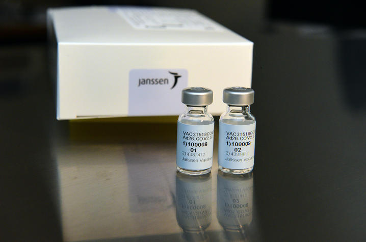 Two vials of the investigation COVID-19 vaccine sit in front of a small box with a Janssen logo. 