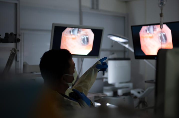 A clinician reviews procedure images on monitors in a hospital treatment room.