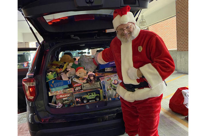photo of UK Police Chief Joe Monroe dressed as Santa Claus in December 2019. He is standing by a vehcile packed with donated toys.