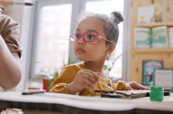 a little girl with glasses painting 