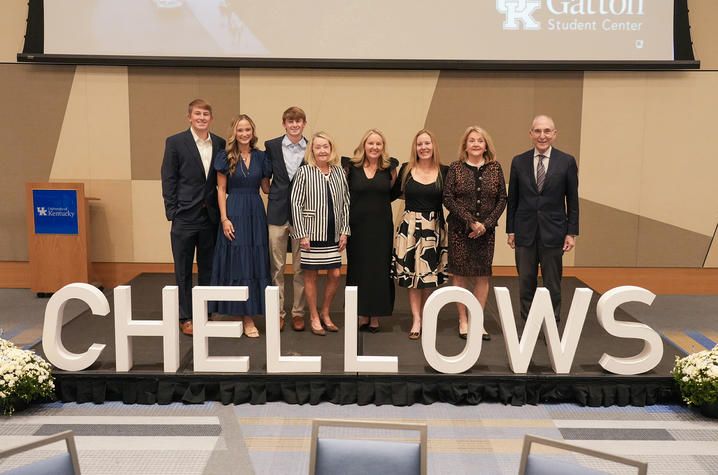 A group of eight people stands together on a stage behind large “CHELLOWS” letters during an event.