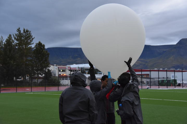 Two people holding a balloon.