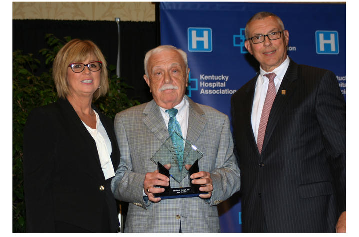 Three people with one holding an award.