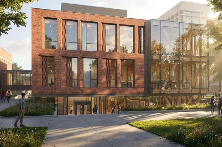 A brick-and-glass campus building with a walkway and landscaping in the foreground.